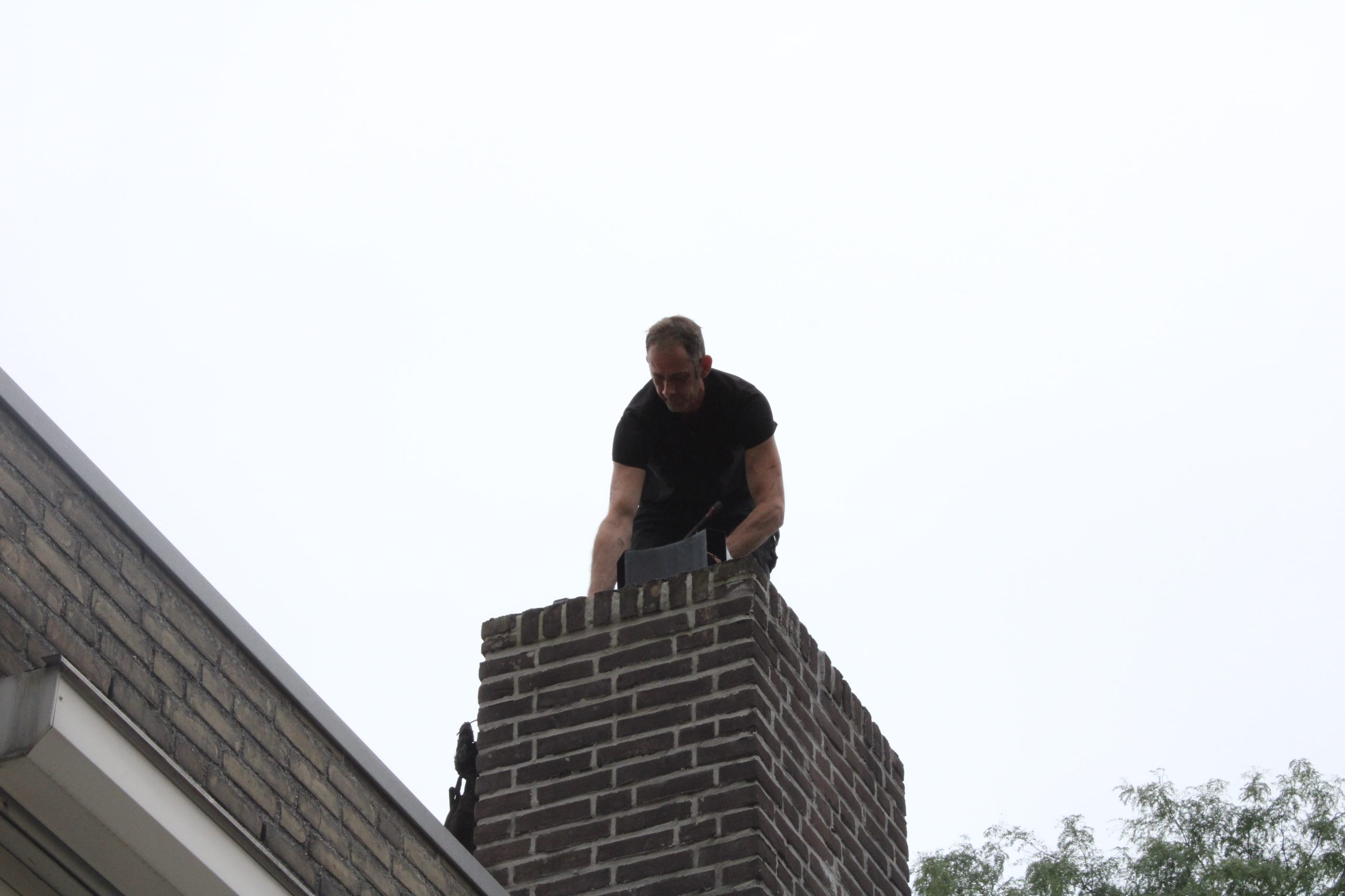 Schoorsteenveger op dak met valbeveiliging